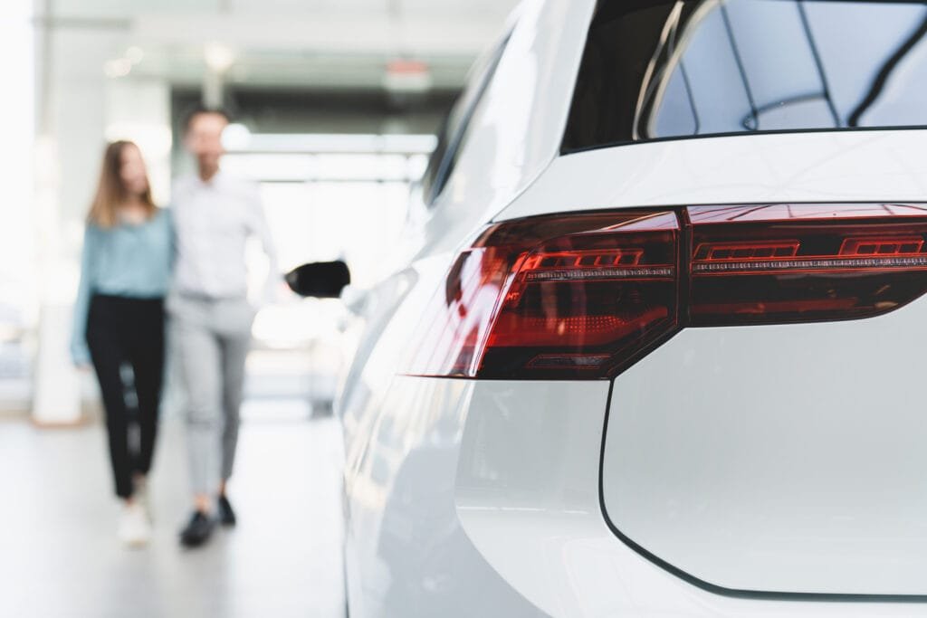 Dealer car shop. Young family couple choosing new car auto before buying purchasing automobile