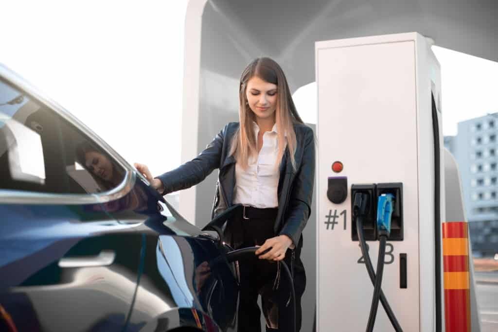 woman in formal clothes, charging an electric vehicle